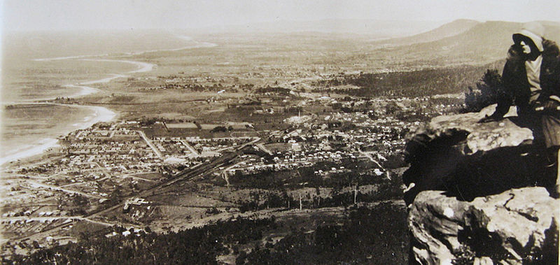 Black and white photograph of the town of Thirroul taken from above with a woman at the right hand side of the image