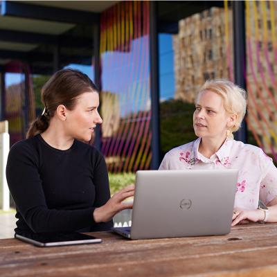 Staff talking outside at a table with a laptop in front of them.
