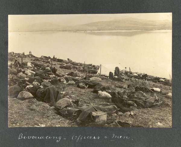 Photograph of soldiers sleeping on the ground captioned 'Bivouacing - Officers and men'