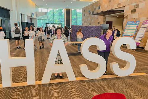 2 librarians standing behind giant letters that spell out "HASS"