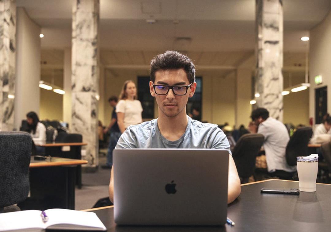 Student on a laptop, seated at a table.