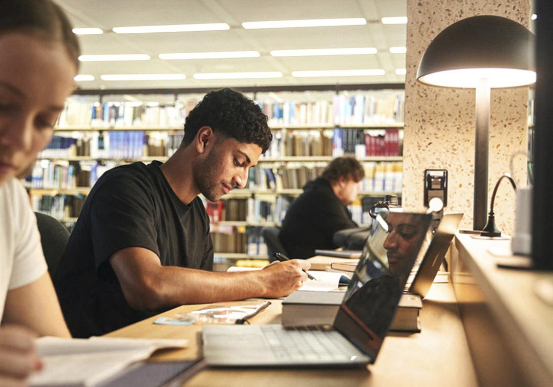 Students studying at a desk with a low-light lamp.