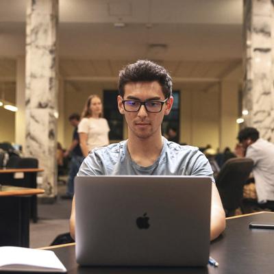 Student on a laptop, seated at a table.