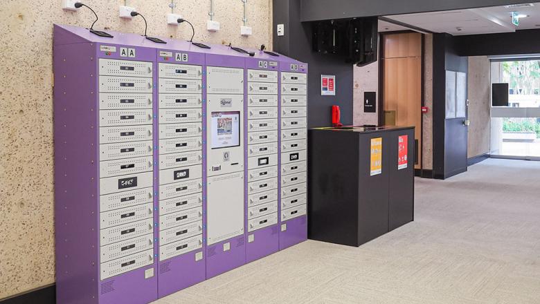 Laptop locker with individual slots to collect and return laptops and a central screen for borrowing.