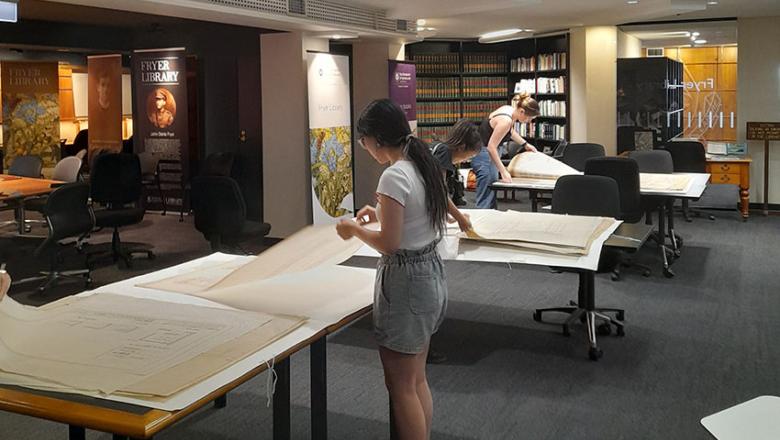 Students examining architectural plans from the Fryer Library collection in the Fryer Library.