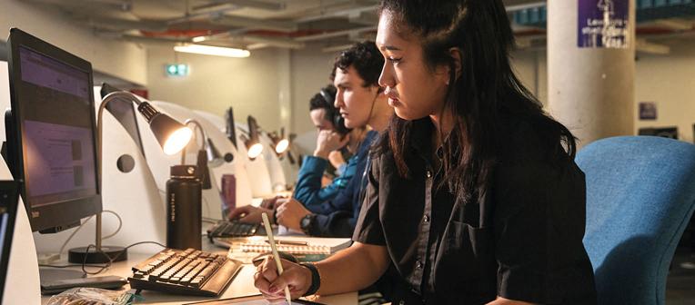 Students at Library computers studying in a low-light study space, Dorothy Hill Engineering and Sciences Library.