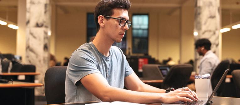 Student using his laptop in a group study area in Duhig Tower.