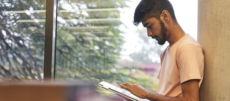 Person typing on a tablet in front of a window