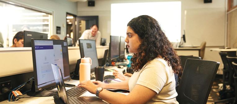 A student working on a laptop in a training room.