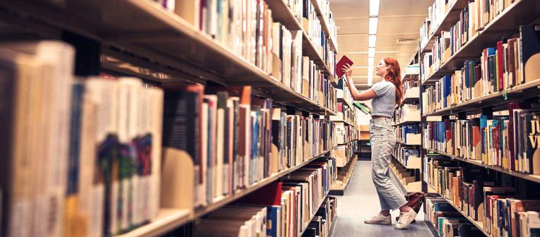 student removing book from library shelf