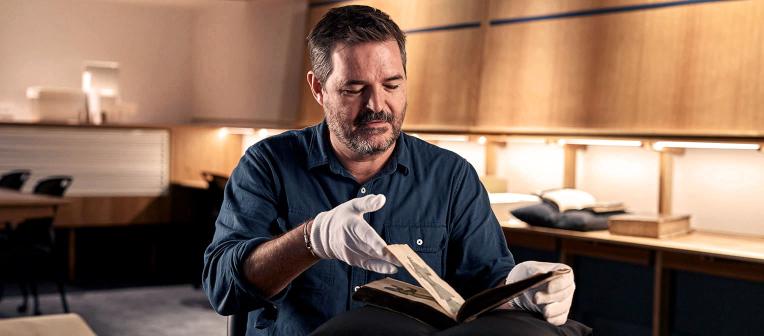 professor geoff ginn with rare book in fryer library