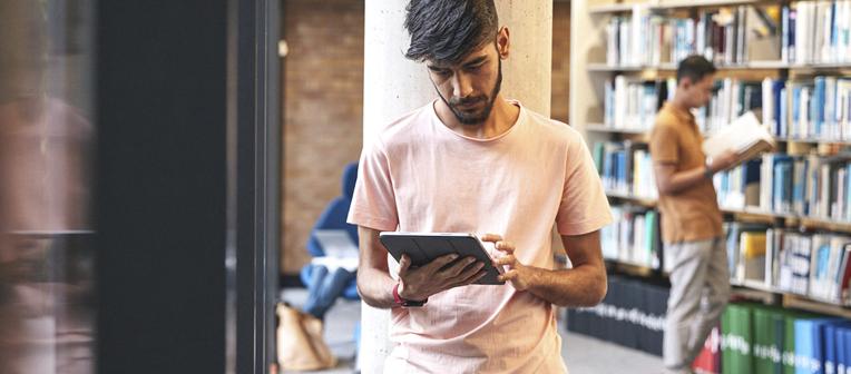 student with tablet device in the library