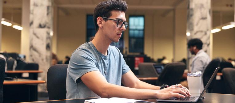 student typing on laptop