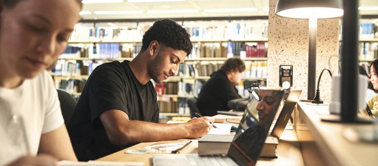 Students studying at a desk with a low-light lamp.