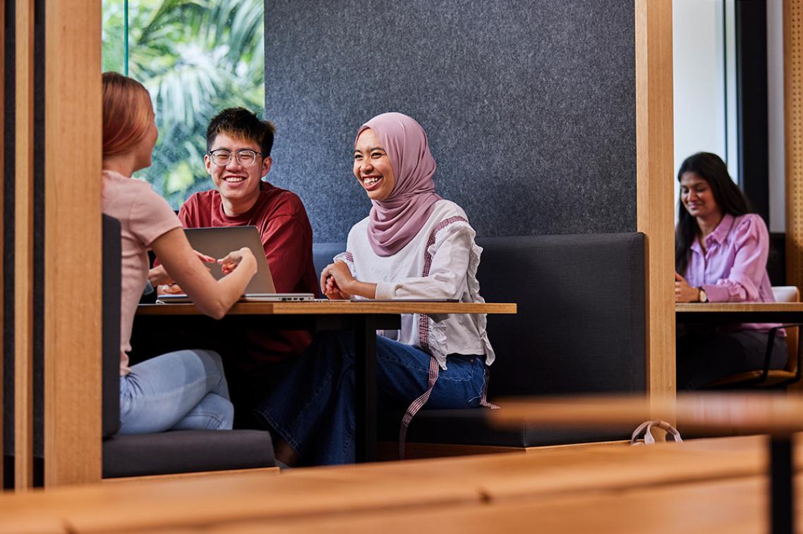 students sitting in a study booth with a laptop