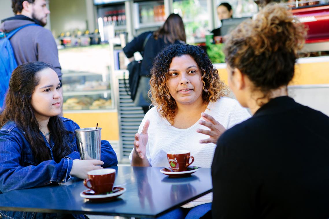 Group of people having a discussion at a table with coffee