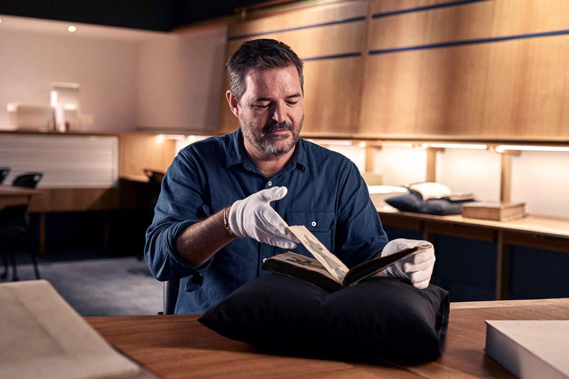 professor geoff ginn with rare book in fryer library