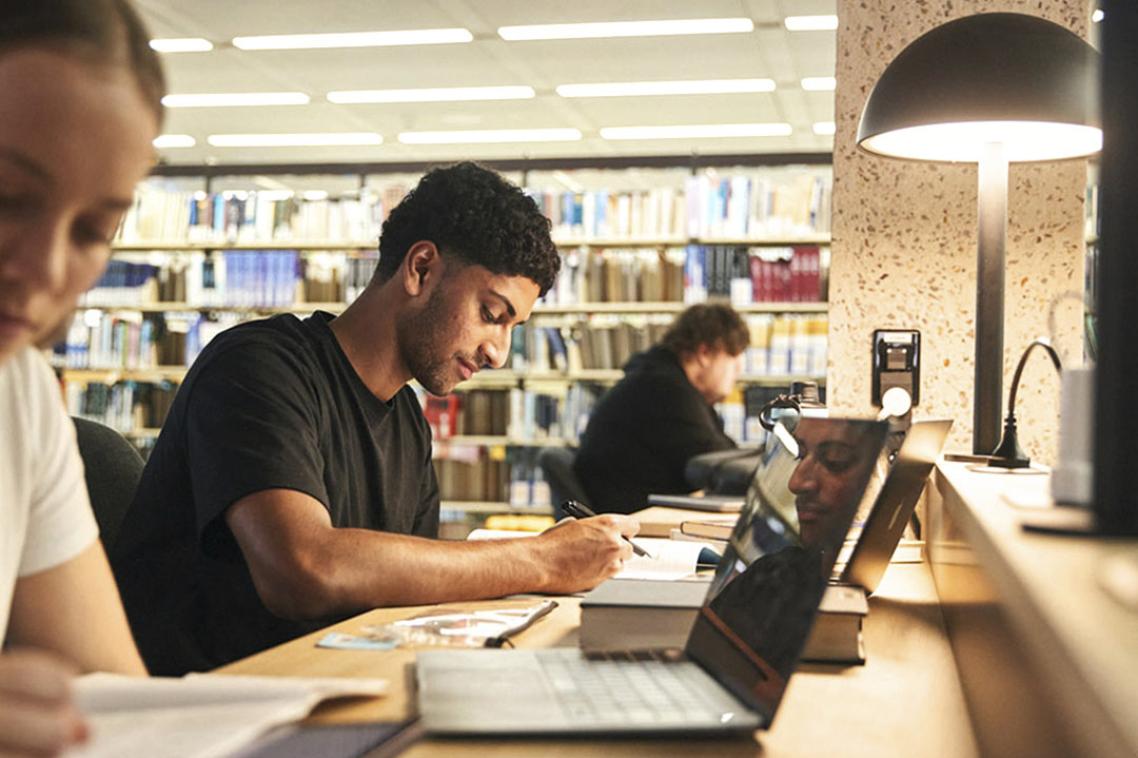 Students studying at a desk with a low-light lamp.