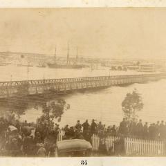 Image of people standing at North Quay looking at flooded Brisbane River and Victoria Bridge, South Brisbane in the background.